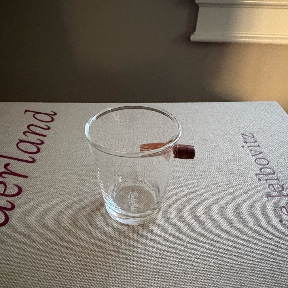 Glass shot glass pierced by copper bullet